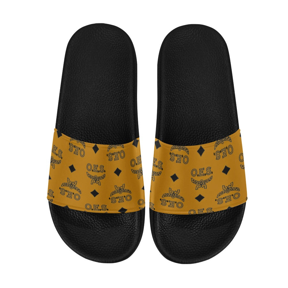 Black slides with yellow patterned straps on a white background