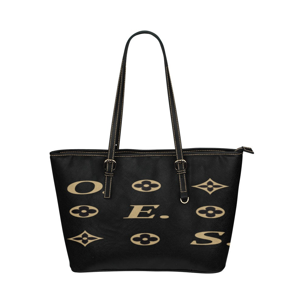 A black leather tote bag with gold text and symbols pattern on the surface.